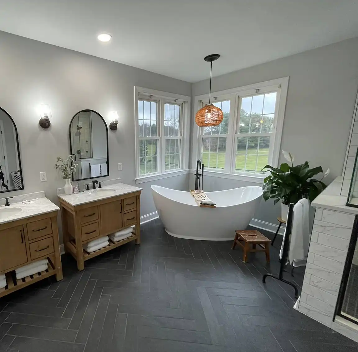 Beautiful bathroom with soaking tub, dual vanities and black tiled floor